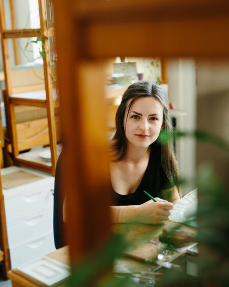 Porträtfoto von KPM Mitarbeiterin Michelle Sosna, fotografiert durch den Rahmen eines Stuhls