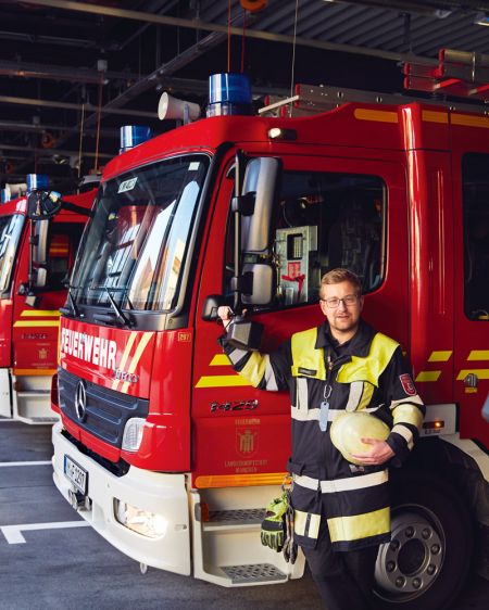 Martin Lammers, Freiwilliger bei der Feuerwehr München, steht vor Feuerwehrfahrzeug