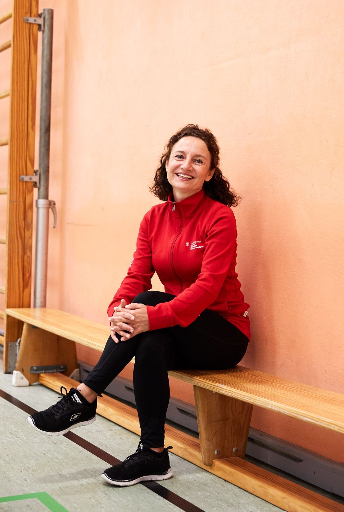 Fitness trainer sitting on bench in a gym