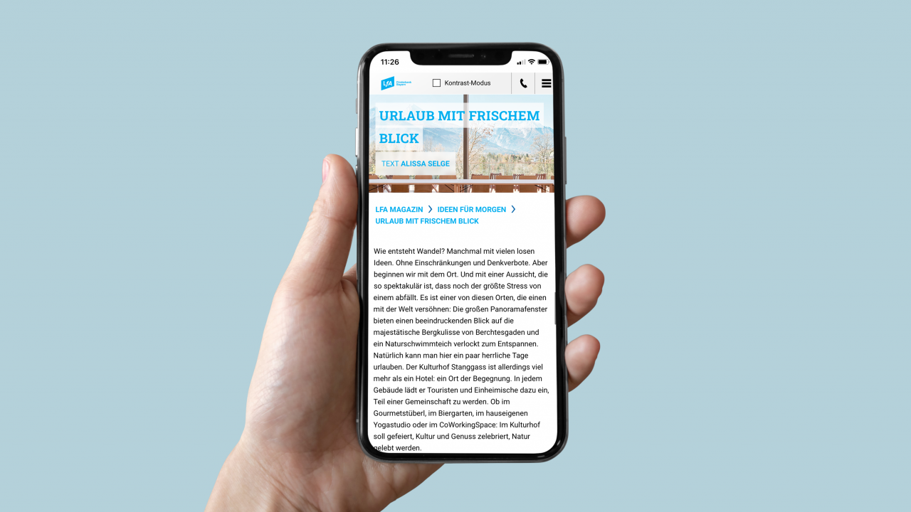 Hand hält Smartphone, das Artikelseite aus dem LfA Online-Magazin anzeigt