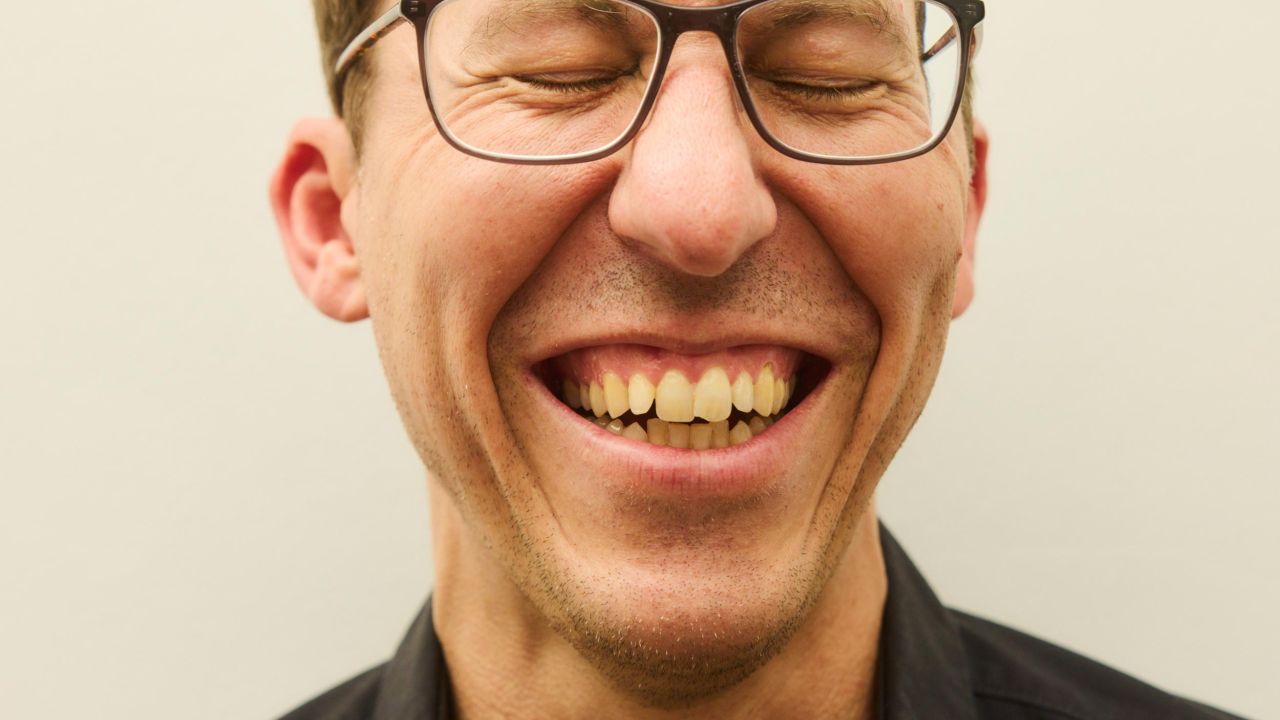 Nahaufnahme des lachenden Gesichts eines Mannes mit Brille, dessen Augen geschlossen sind