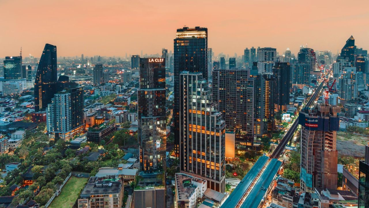 Luftaufnahme zeigt die dichte Skyline von Bangkok bei Sonnenuntergang mit einem BTS Skytrain